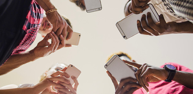 Gruppe von Personen hält Smartphones im Kreis – Symbol für Vernetzung und digitale Kommunikation in der Medienbranche.