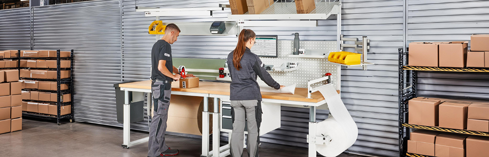 Modularer Packtisch mit zwei Arbeitsplätzen, Abroller, Ablagen und ergonomischem Zubehör – ideal für Verpackung und Versandprozesse in Industrie und Logistik.