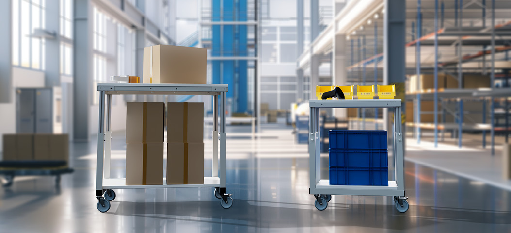 Zwei Tischwagen in einer Lagerhalle, einer beladen mit Kartons, der andere mit gelben Aufbewahrungsboxen und blauen Sichtlagerkästen.